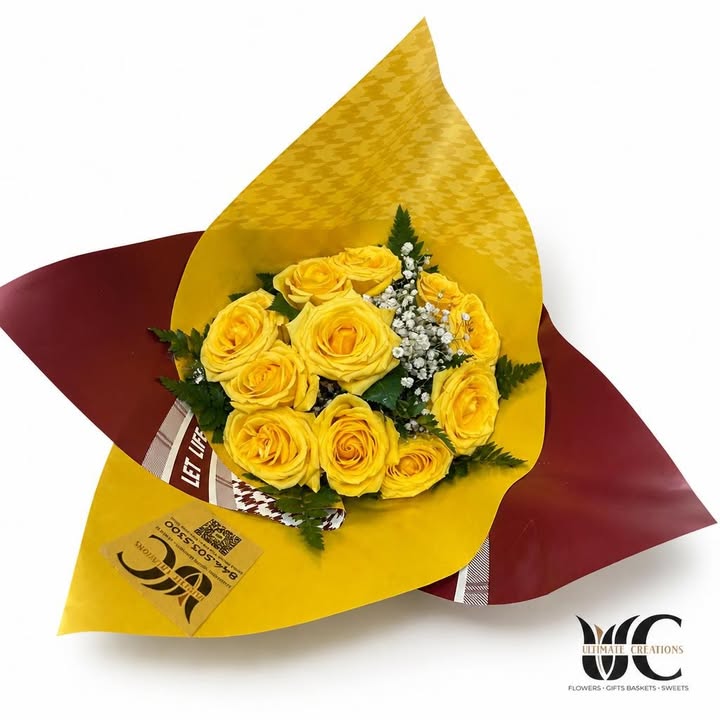 Yellow rose bouquet with white filler flowers, greenery, and layered yellow and burgundy wrapping.