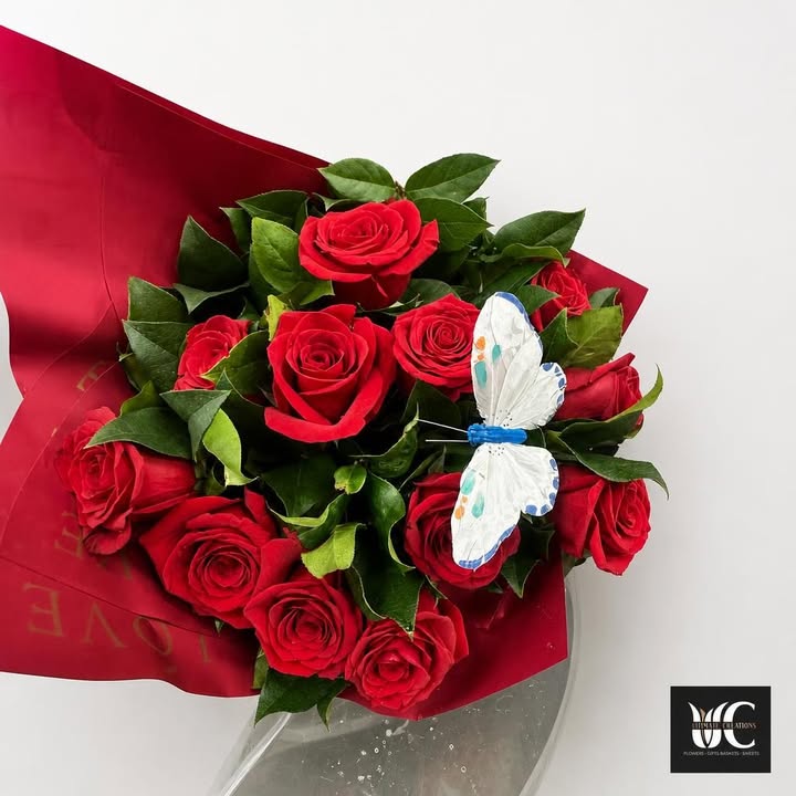 Red rose bouquet with greenery, red wrap, and a white-and-blue butterfly accent