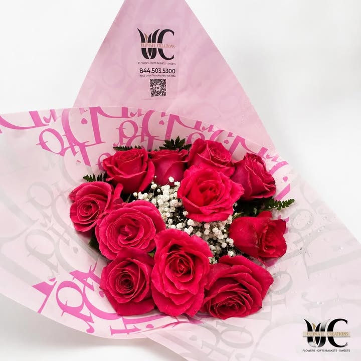 Bouquet of vivid pink roses with white filler flowers and greenery in decorative pink wrapping