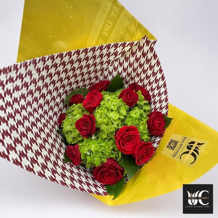 Red rose bouquet with green blooms in patterned paper and yellow wrap