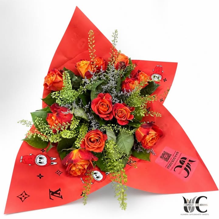 Red and orange rose bouquet with greenery and red patterned wrapping