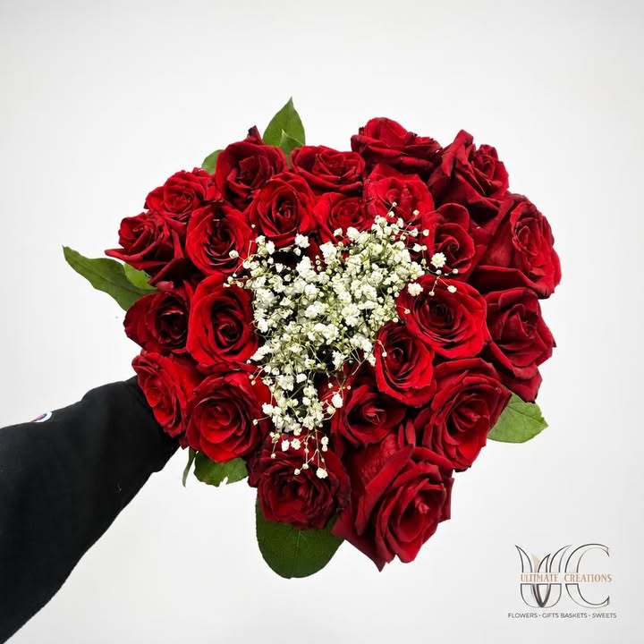 Lush bouquet of red roses with white filler flowers and greenery.