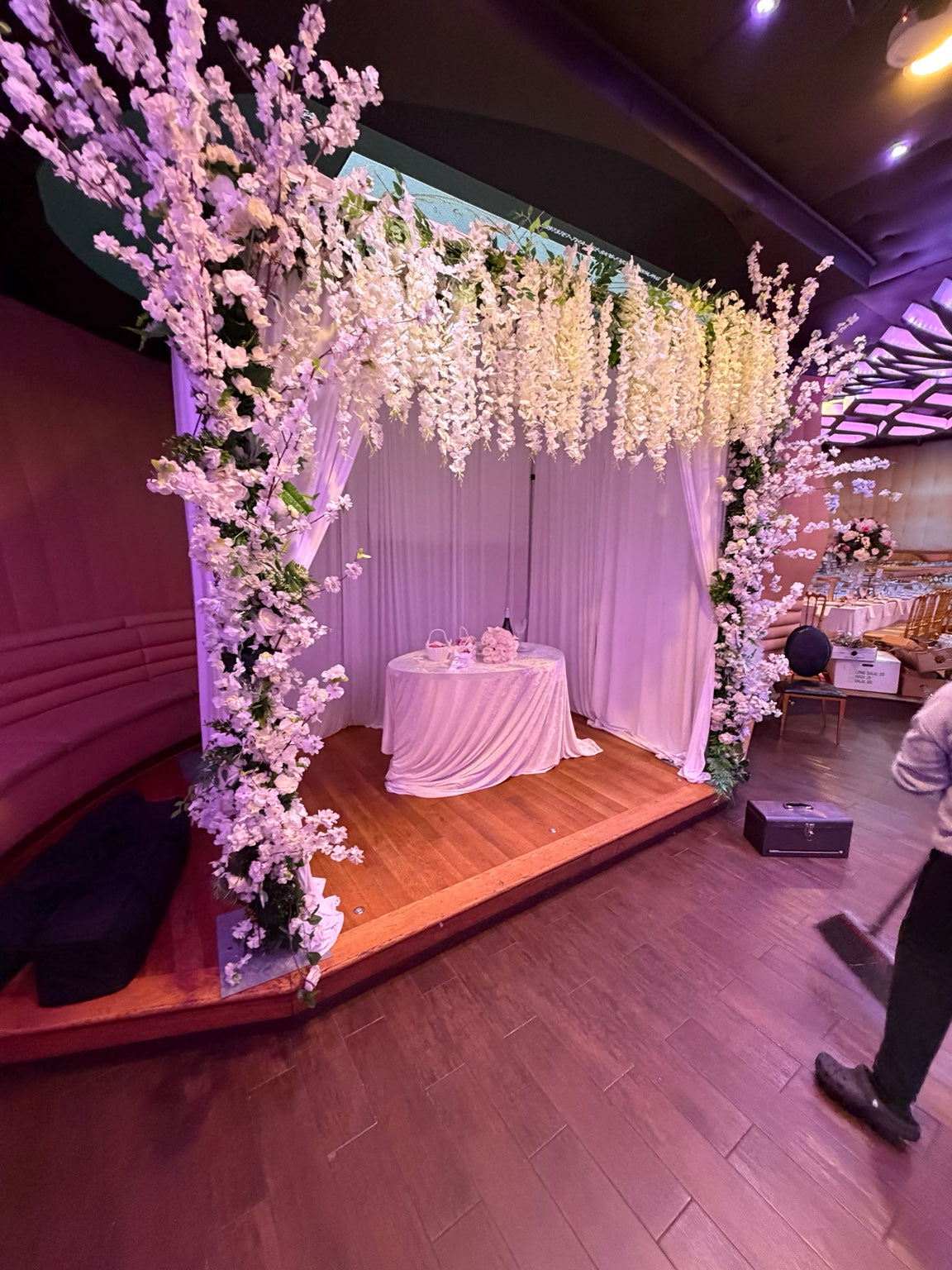 Wide view of Diana and Sam's white floral wedding ceremony canopy, hanging blossoms and draped backdrop at Oligarch Catering Hall in Richmond Hill, Queens