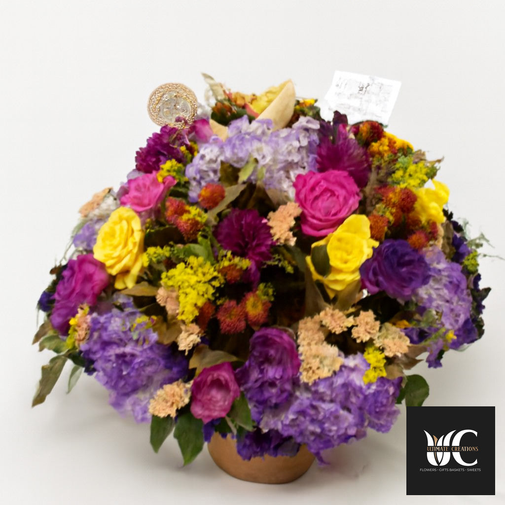 Round colorful floral centerpiece with purple, pink, yellow, and lavender flowers in a low vase.