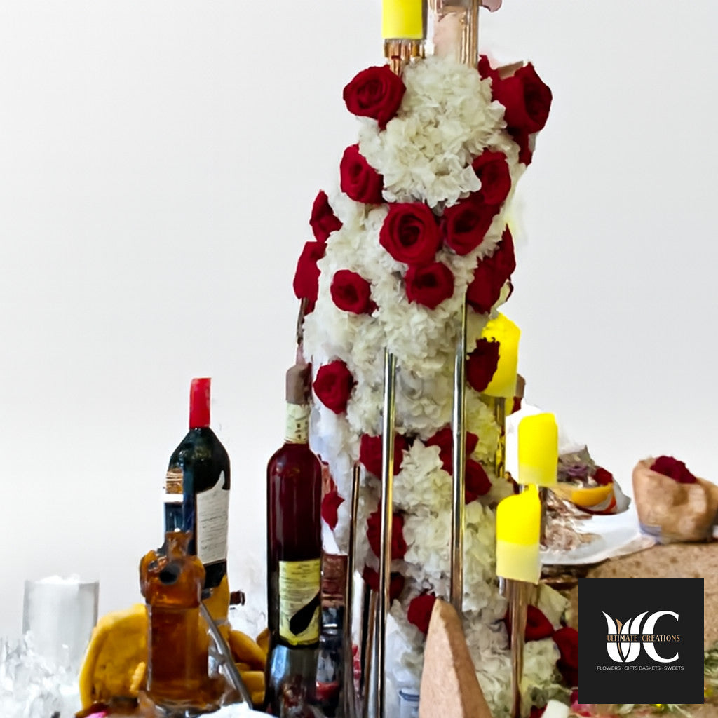 Tall floral table display with red roses, white flowers, and candle accents on a decorated table.