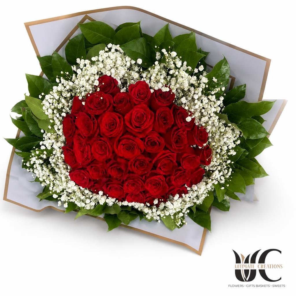 Bouquet of red roses surrounded by baby’s breath and green leaves.