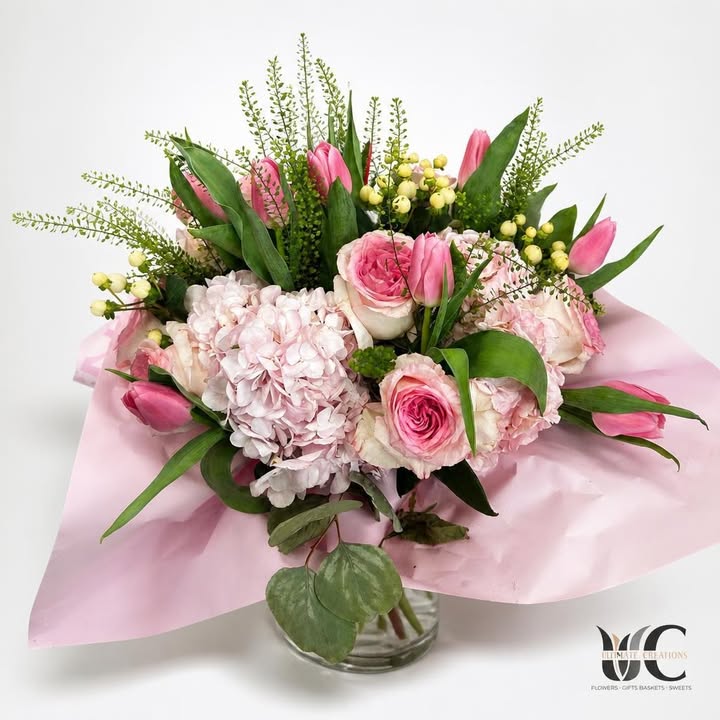 Wrapped bouquet with pink and white flowers, greenery, and yellow accents