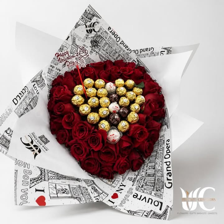 Round bouquet of red roses with assorted wrapped chocolates in illustrated white paper.