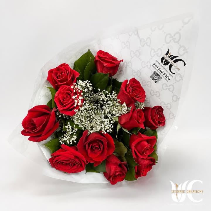 Bouquet of red roses with white filler flowers and green foliage in white wrapping