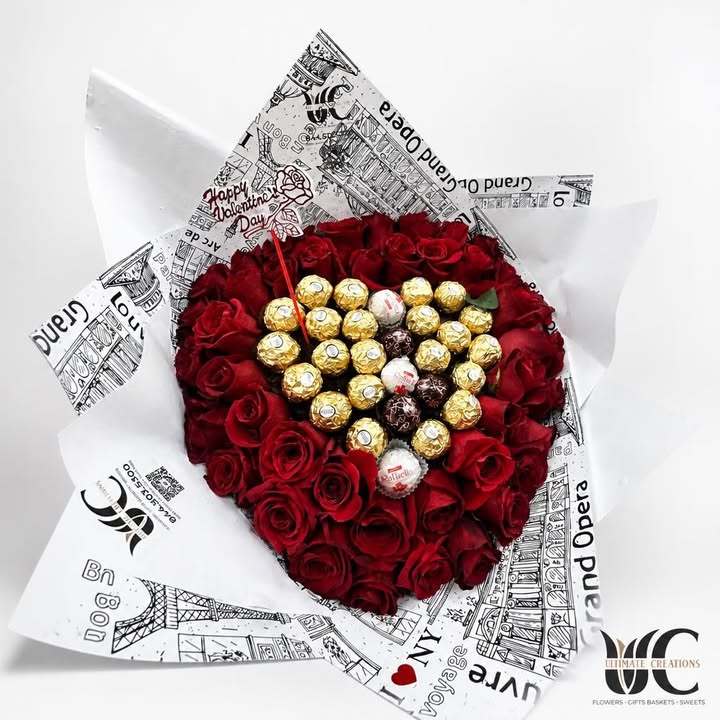 Bouquet of red roses surrounding assorted gold-wrapped chocolates in illustrated white paper wrapping