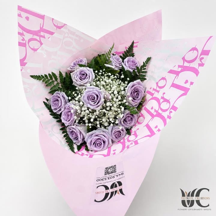 Lavender roses with white filler flowers and greenery in pink-and-white wrapping