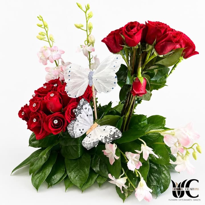Red rose arrangement with pink blossoms, butterfly accents, and greenery
