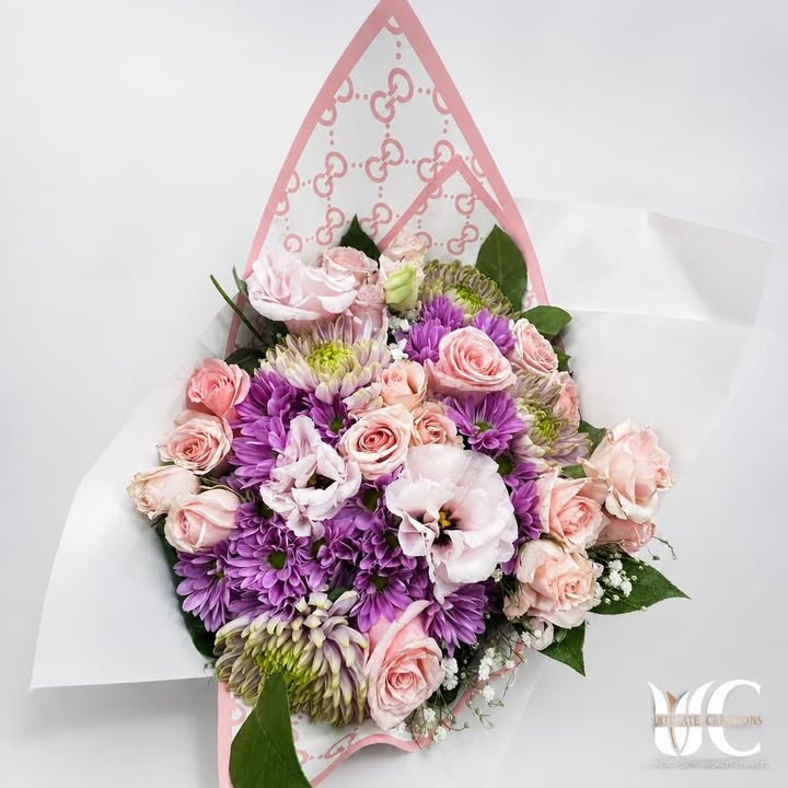 Lush pink and lavender bouquet wrapped in pink-and-white paper.