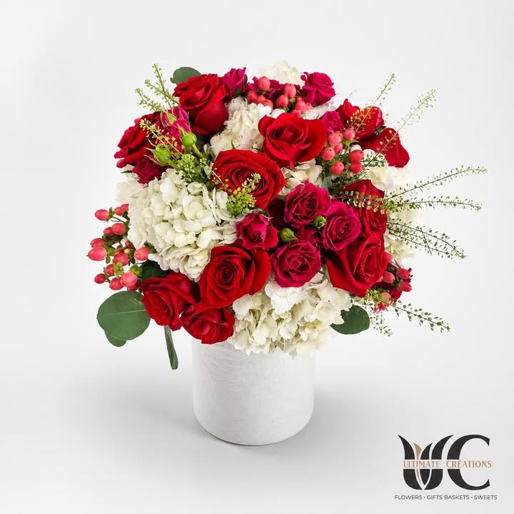 Red and white bouquet with pink accents and greenery.