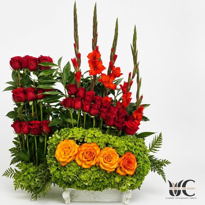 Lush centerpiece with red roses, orange blooms, and green flowers