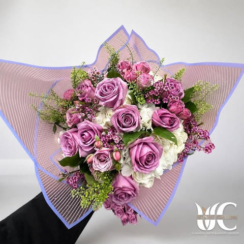 Red rose arrangement with pale pink flowers, greenery, and butterfly accents