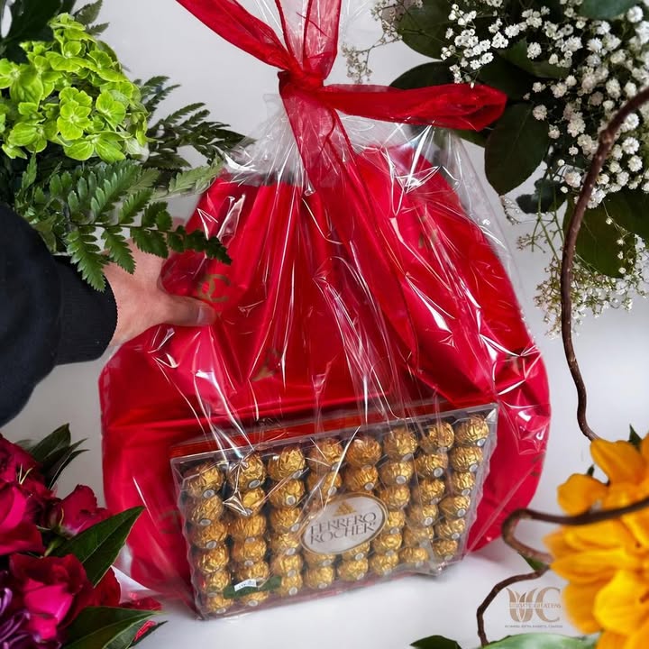Wrapped floral gift arrangement with chocolates, colorful flowers, and greenery