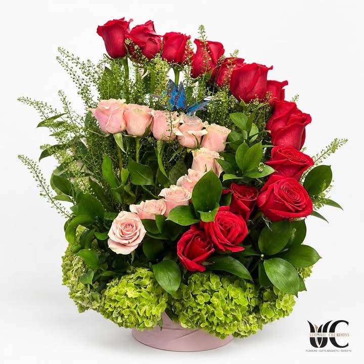Lush red and blush rose arrangement with greenery and a blue butterfly accent