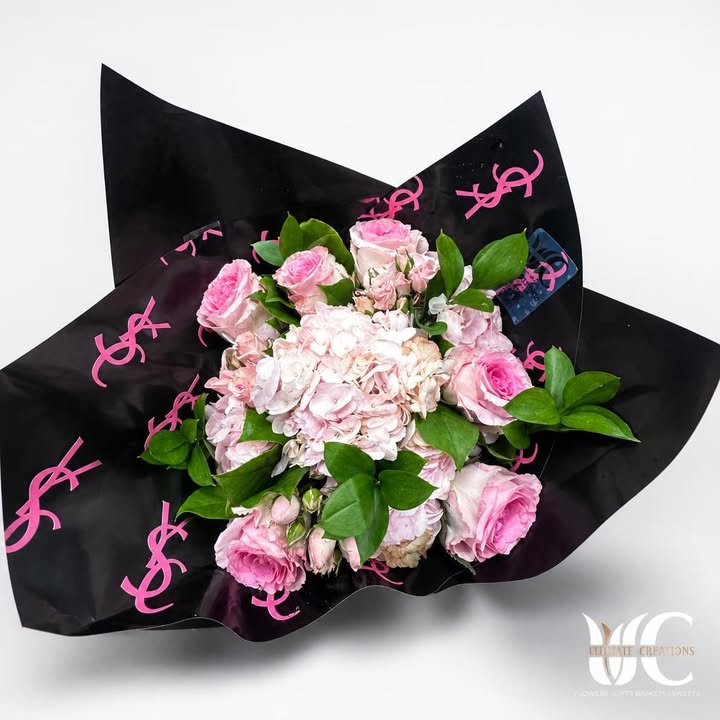 Pink and white flower bouquet with greenery in black wrapping with pink accents.