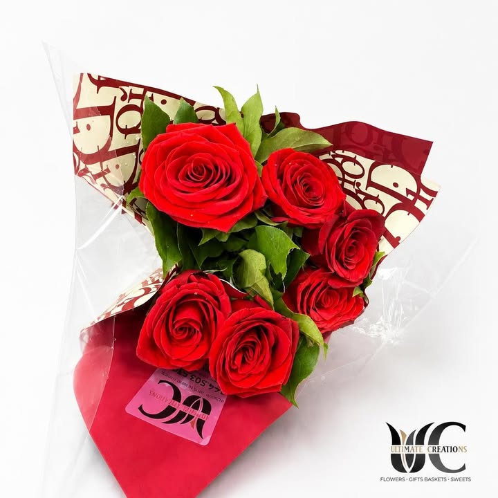 Wrapped bouquet of red roses with green foliage and decorative packaging