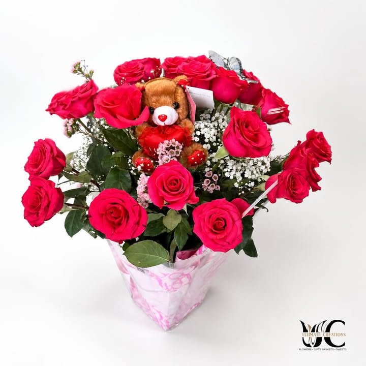 Red and pink rose bouquet with teddy bear, white filler flowers, and pink wrapping.