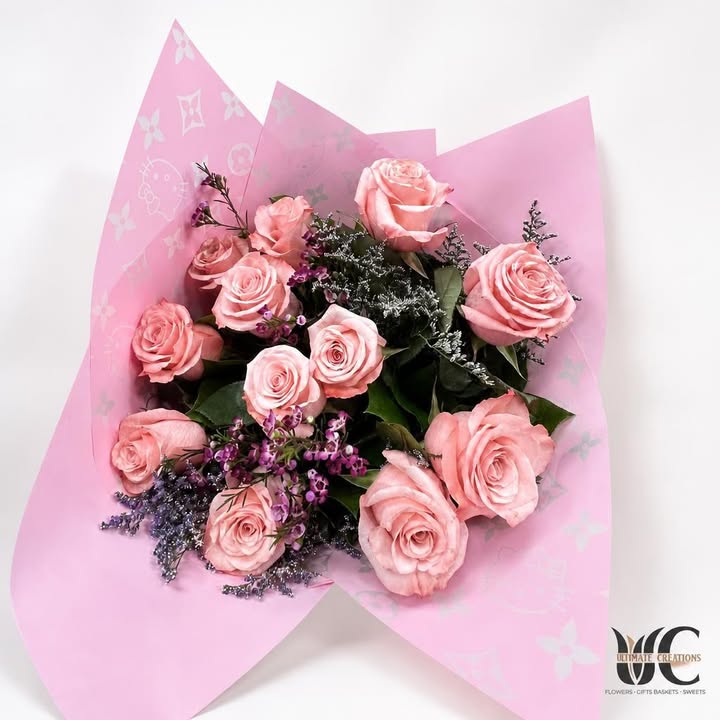 Pink rose bouquet wrapped in patterned pink paper with purple and white accents