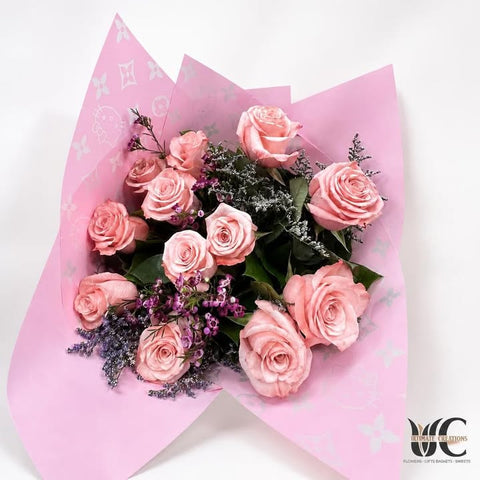 Pink rose bouquet wrapped in patterned pink paper with purple and white accents