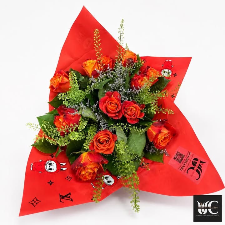 Red and orange rose bouquet with green foliage and lavender filler in red wrapping