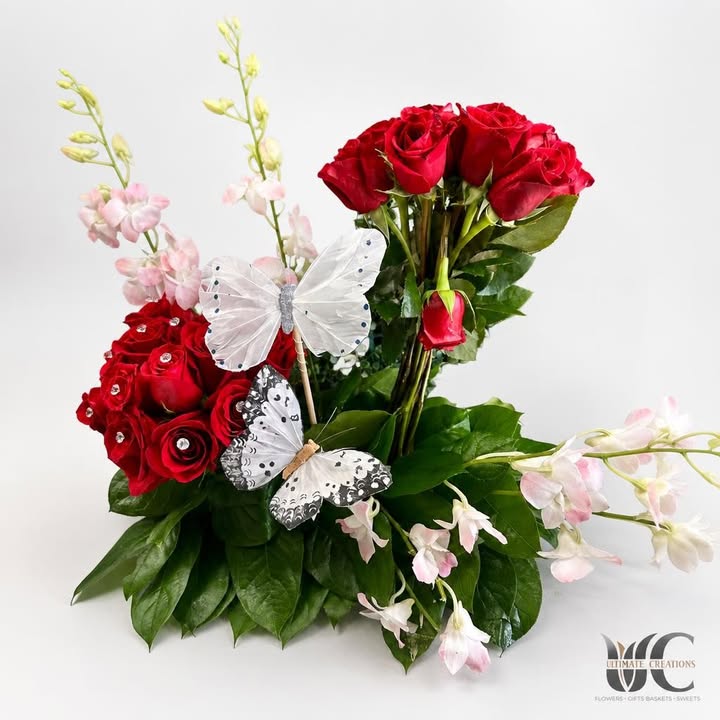 Red roses with pale blossoms, greenery, and butterfly accents