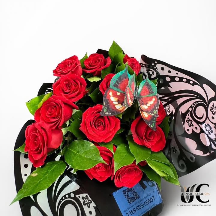 Wrapped bouquet of red roses with greenery and a butterfly accent