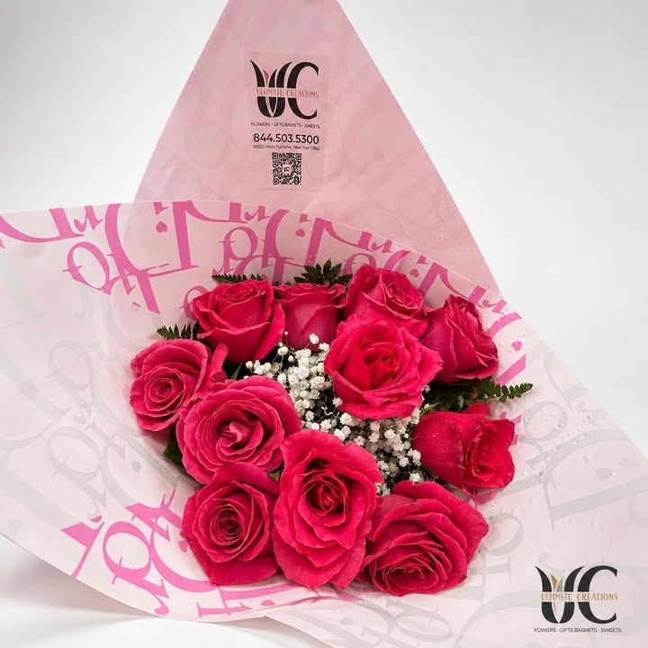 Wrapped bouquet of vivid pink roses with white filler flowers and greenery