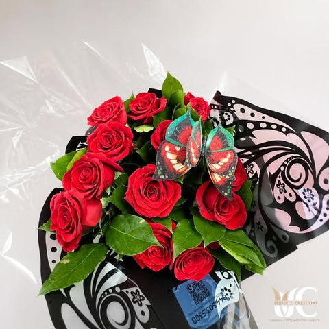 Red rose bouquet with greenery, butterfly accent, and patterned wrapping