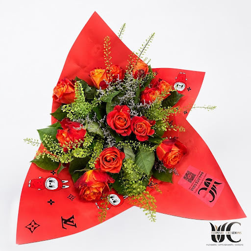 Red and orange-toned rose bouquet with foliage and red wrapping.