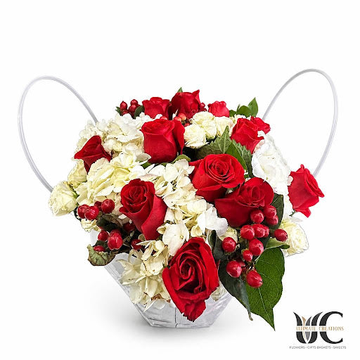 Red roses and white blooms in a handled container with greenery.