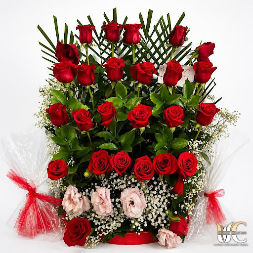 Lush red rose arrangement with soft pink accents, white filler flowers, and greenery.