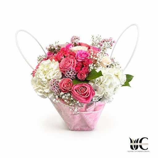 Pink and white floral arrangement with roses and greenery.