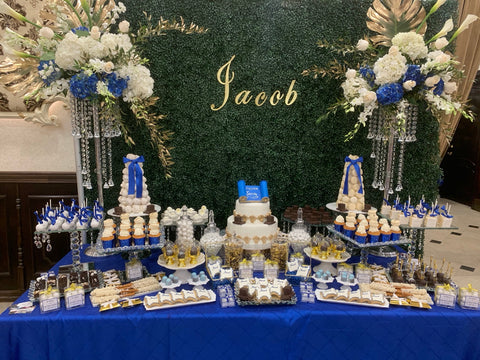 Jacob Bar Mitzvah dessert display with green hedge backdrop, blue and white florals, gold accents and custom sweets by Ultimate Creations NY