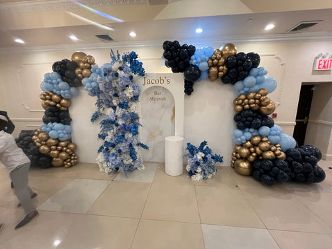 Jacob's Bar Mitzvah backdrop with black, light blue and gold balloons and blue-white florals in Queens NY
