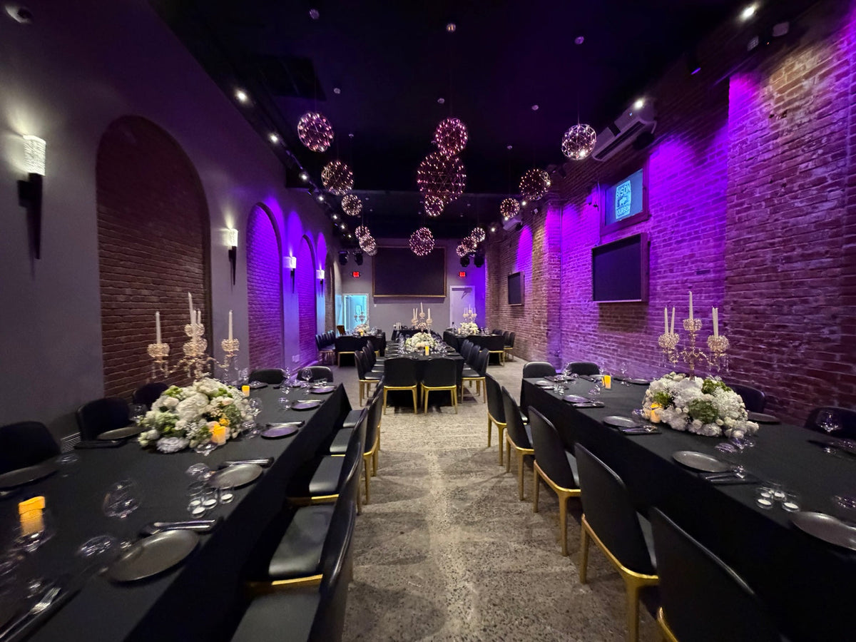 Luxury Jewish wedding reception at Bison & Bourbon Brooklyn with black tables, gold chairs, white florals and purple uplighting