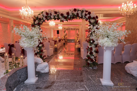 N&E wedding ceremony aisle at Floral Terrace with a red and white floral arch, pedestal arrangements and mirrored aisle by Ultimate Creations NY.