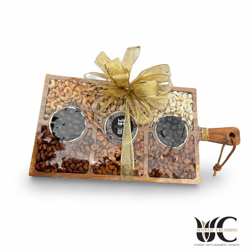 Decorative wooden gift board with assorted nuts and chocolate-covered treats, wrapped with a gold ribbon and bow.