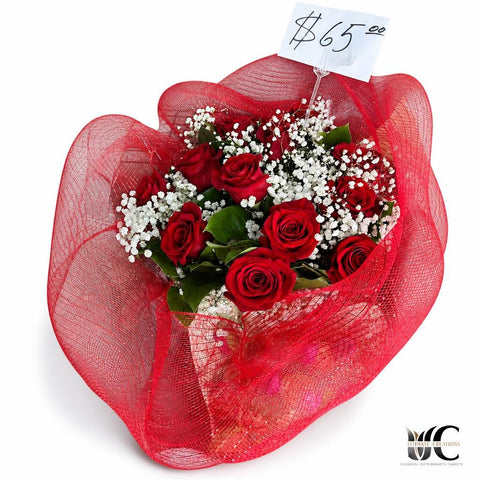 Bouquet of red roses with baby’s breath and green leaves wrapped in red mesh.