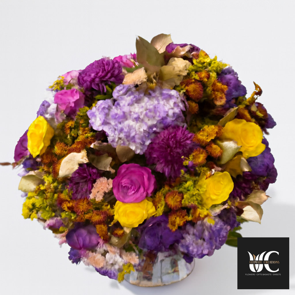 Colorful mixed flower arrangement in a vase with purple, yellow, pink, and lavender blooms.