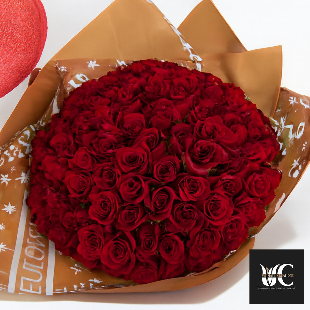 Large bouquet of red roses wrapped in brown paper with white accents.