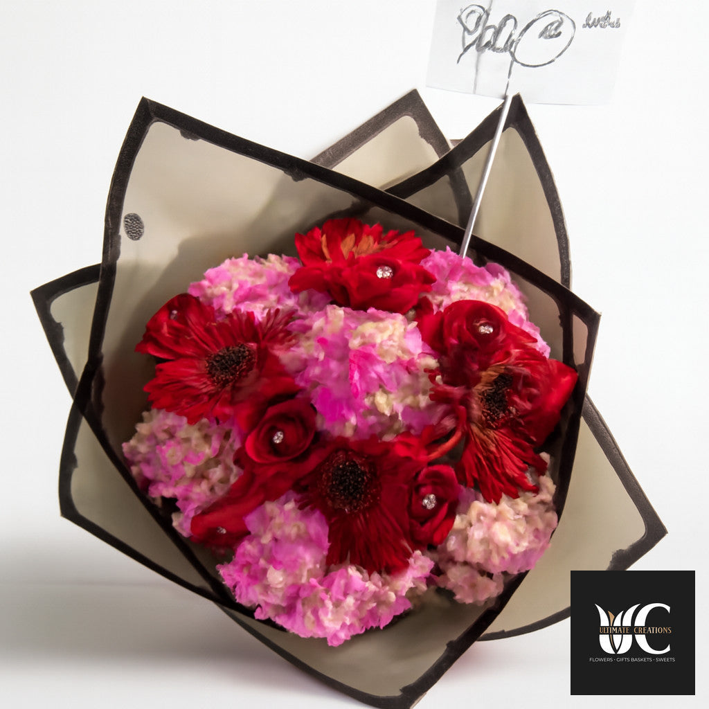 Modern bouquet with red and pink flowers wrapped in black-edged paper.