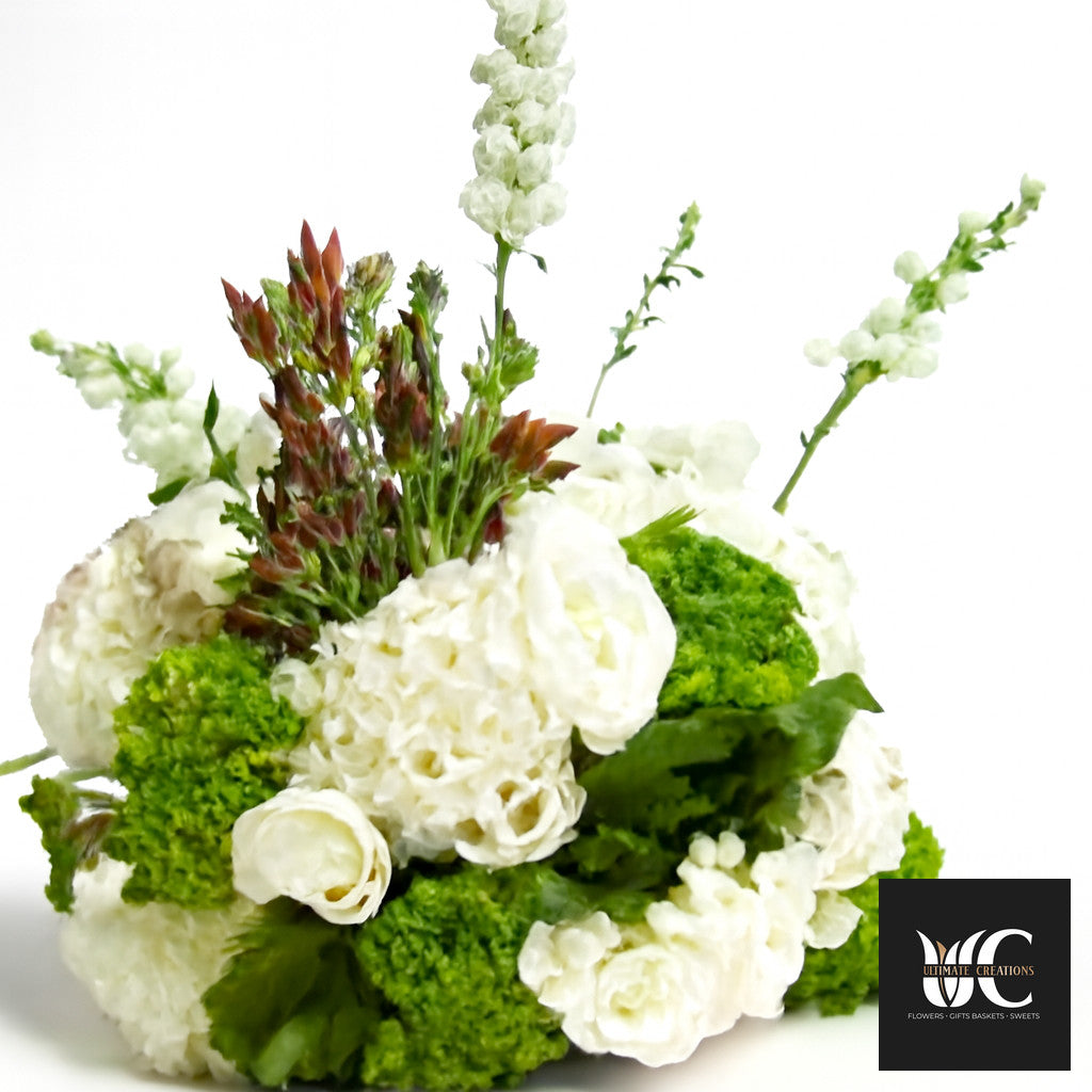 White and green floral centerpiece with layered blooms and tall airy accents.