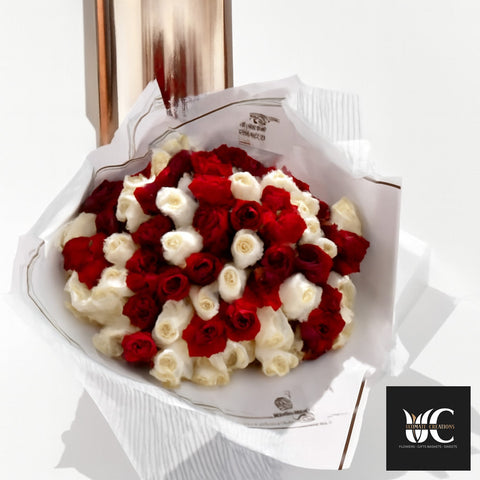 Hand-tied bouquet of red and white roses wrapped in white paper.