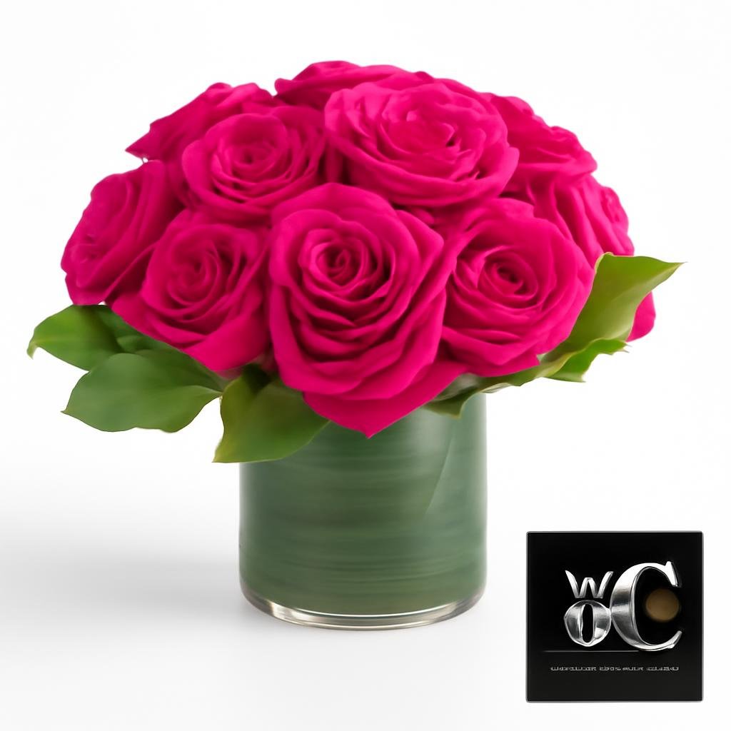 A round vase arrangement of hot pink roses with green foliage in a glass container.