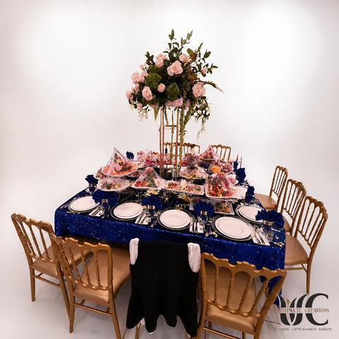 Tall lush floral centerpiece with white and blush flowers above a formal banquet table in a softly illuminated event room.