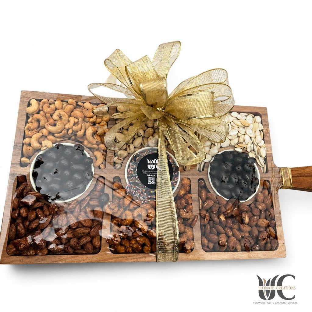 Decorative gift board with assorted nuts, two dipped treats, and a gold ribbon bow.